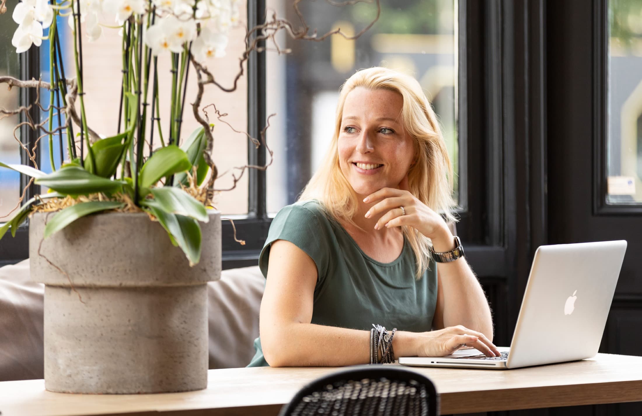 Laura Evers achter haar laptop naast een orchidee bij het raam