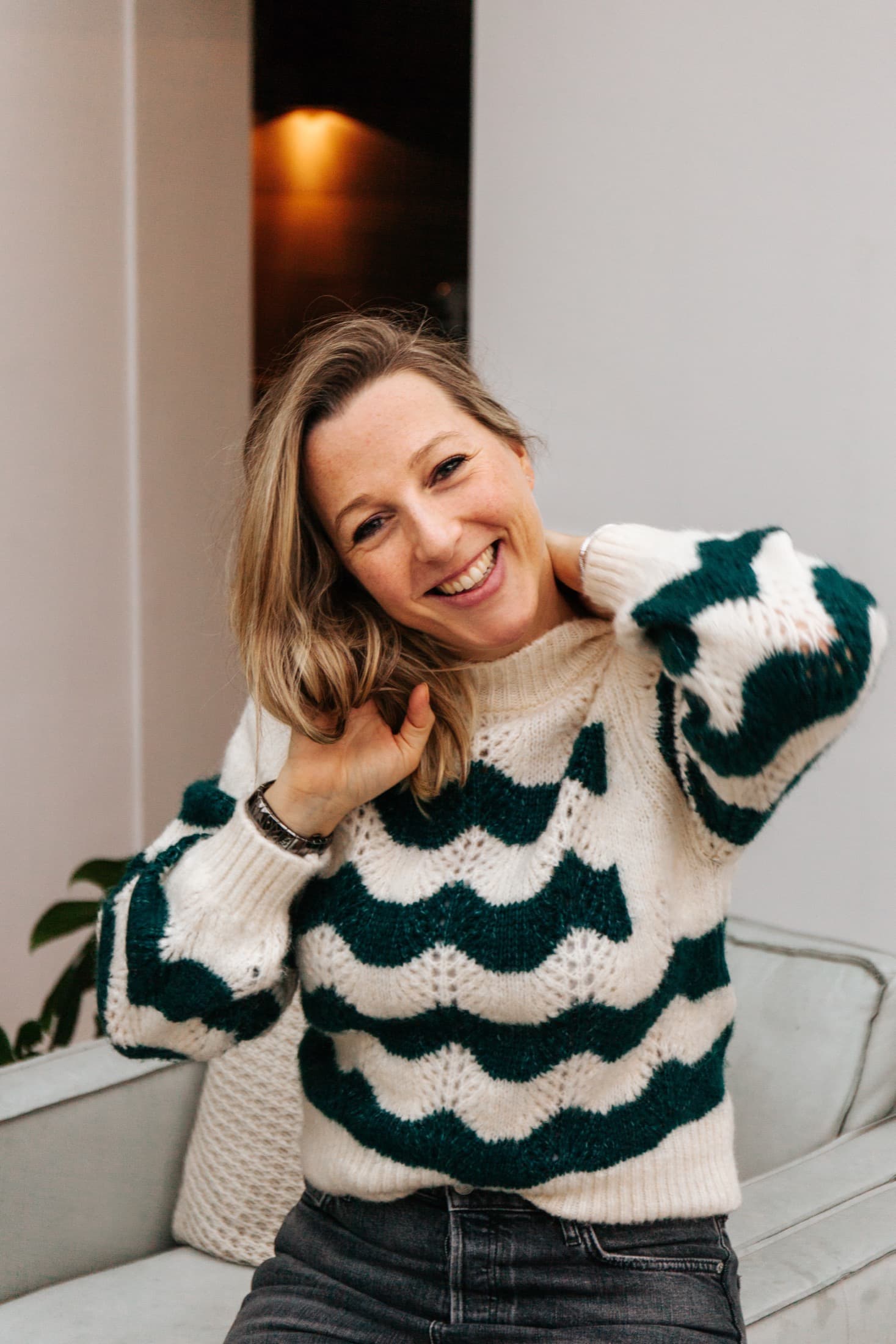 Laura Evers lachend in een groen-witte trui